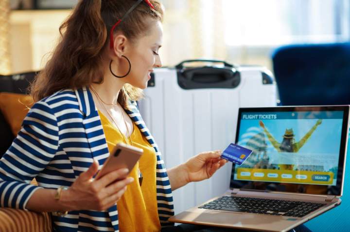 Une personne souriante regardant un smartphone, symbolisant la facilité de réservation en ligne pour un voyage.